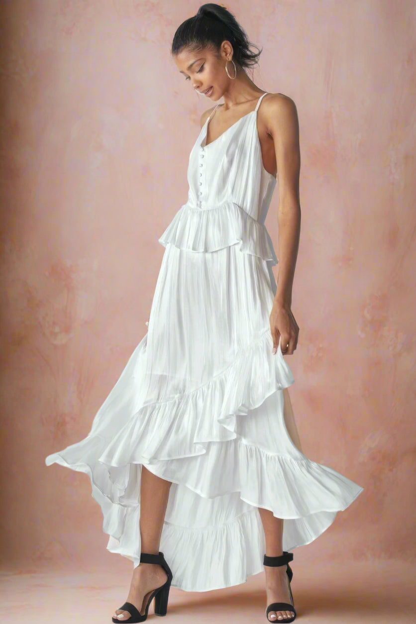 Ásta Modern Shimmering White Unstructured A-Line High-Low Maxi Wedding Dress With Spaghetti Straps, Ruffles, V-Neckline, Buttons, and Peplum Detail by Orange Blossom Bridal.