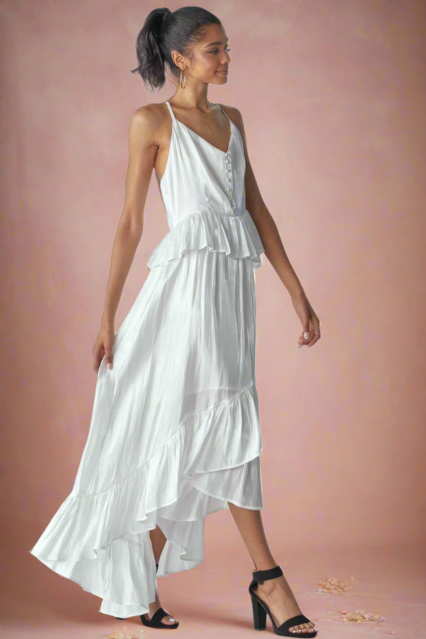 Ásta Modern Shimmering White Unstructured A-Line High-Low Maxi Wedding Dress With Spaghetti Straps, Ruffles, V-Neckline, Buttons, and Peplum Detail by Orange Blossom Bridal.